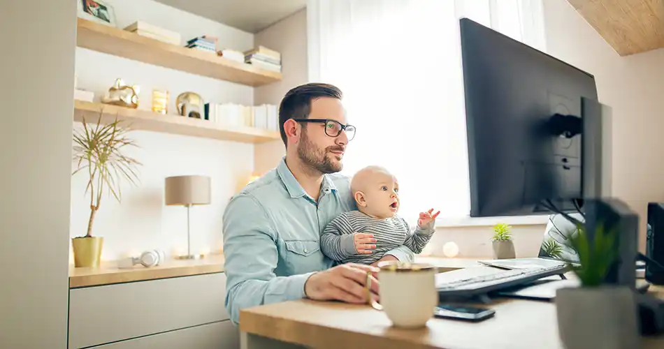 Mitarbeiter im Home Office mit Baby auf dem Schoss